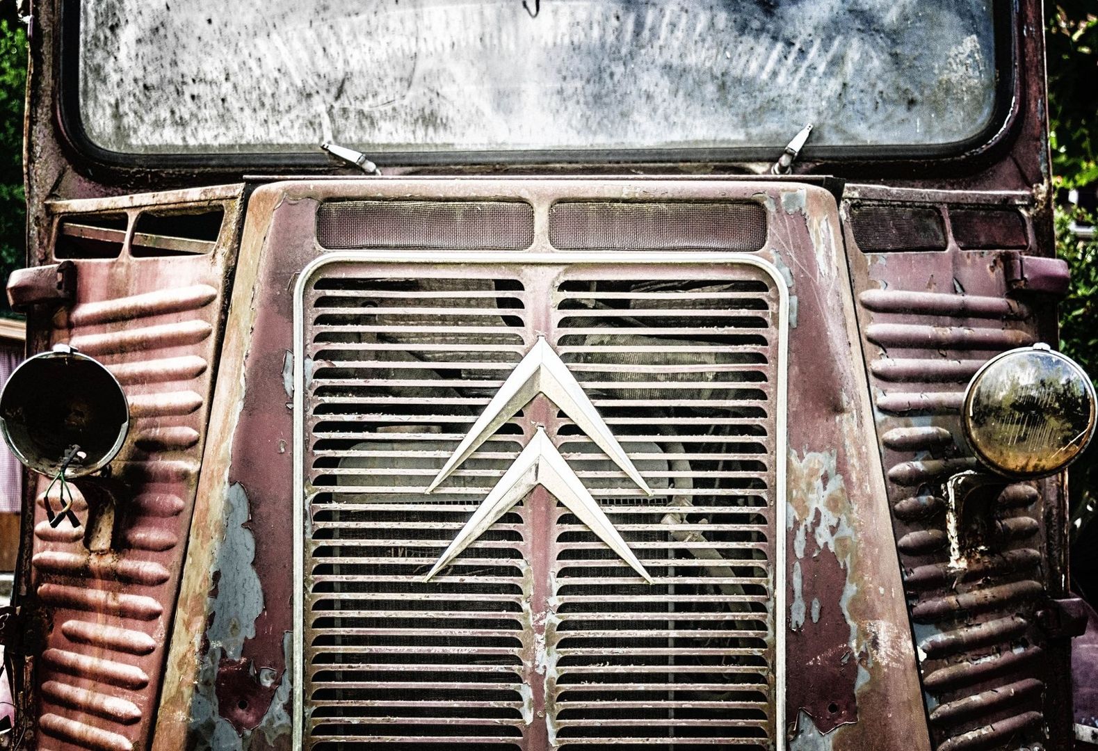 Nahaufnahme der verwitterten Front eines alten Citroën mit Doppelwinkel-Emblem