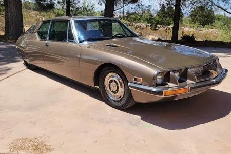 Bronzefarbener Citroën SM mit markanter Front unter Bäumen
